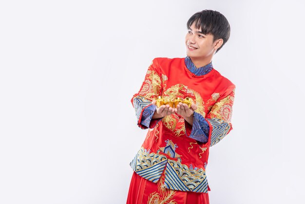 Un homme porte un costume Cheongsam donne de l'or à son parent pour avoir de la chance au nouvel an chinois