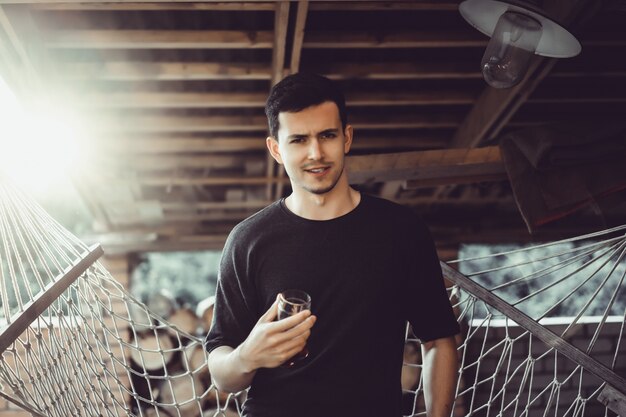 Homme. portrait gros plan, sourire, yeux rusés, un verre dans les mains