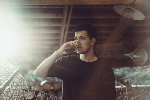 Homme. portrait gros plan, sourire, yeux rusés, un verre dans les mains