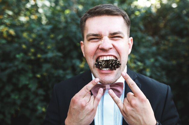 Homme posant avec des cônes de pin en bouche