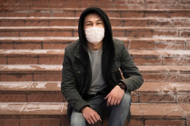 Homme posant dans les escaliers tout en portant un masque médical