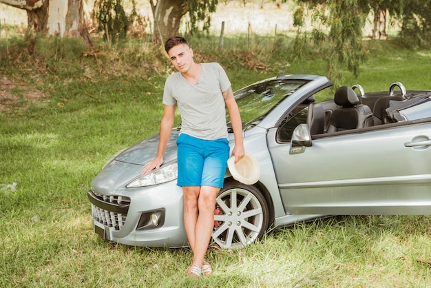 Photo gratuite homme posant devant sa voiture