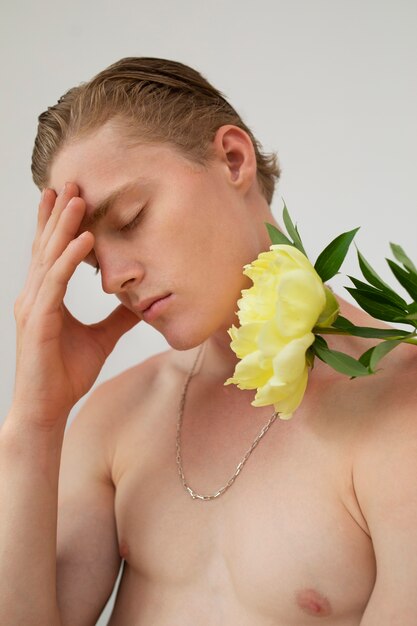 Homme posant avec une fleur en studio plan moyen