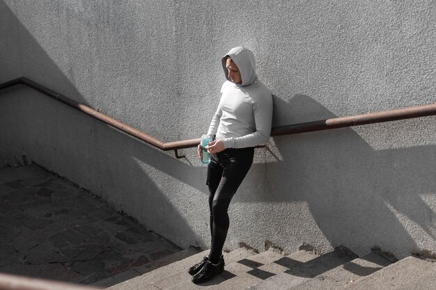 Homme posant la mode dans les escaliers avec une bouteille d'eau