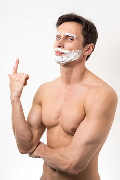 Homme posant avec de la mousse à raser sur le visage