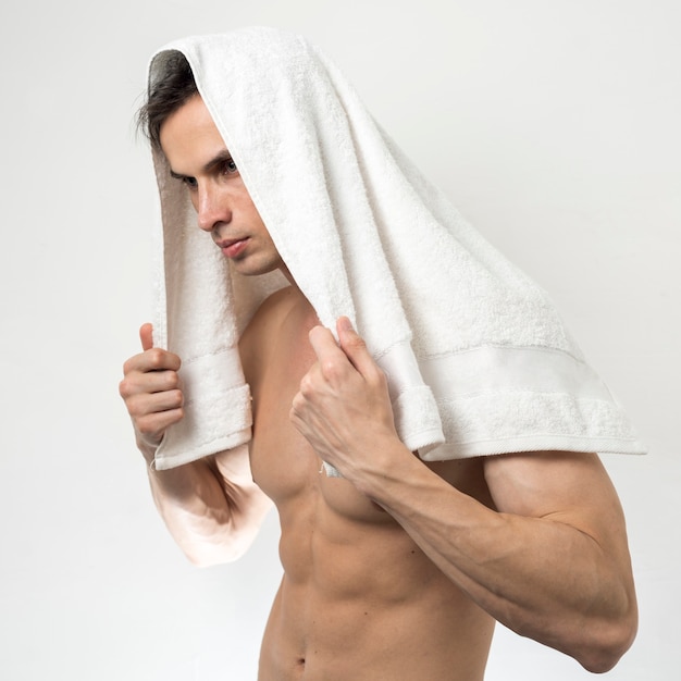 Homme posant avec une serviette de bain sur la tête