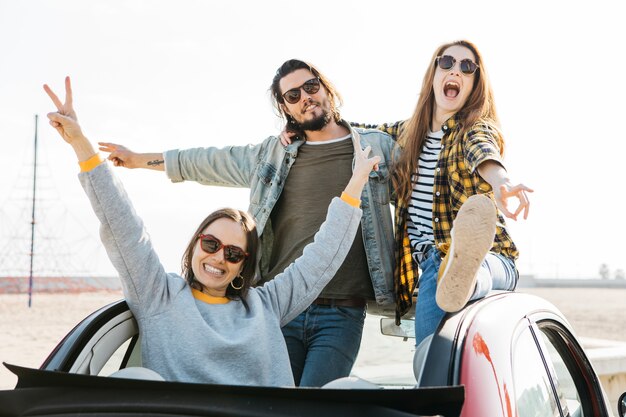 Homme positif et femmes pleurant s&#39;amusant et se penchant de l&#39;auto