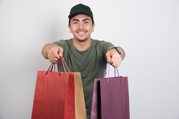 Homme positif avec des sacs à provisions sur fond blanc.