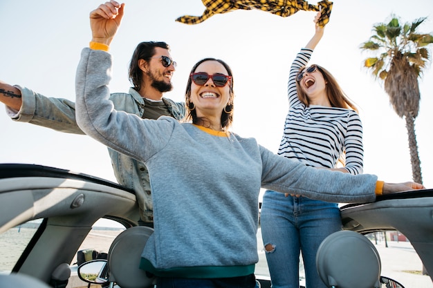 Photo gratuite homme positif et souriant des femmes s'amusant et se penchant de voiture