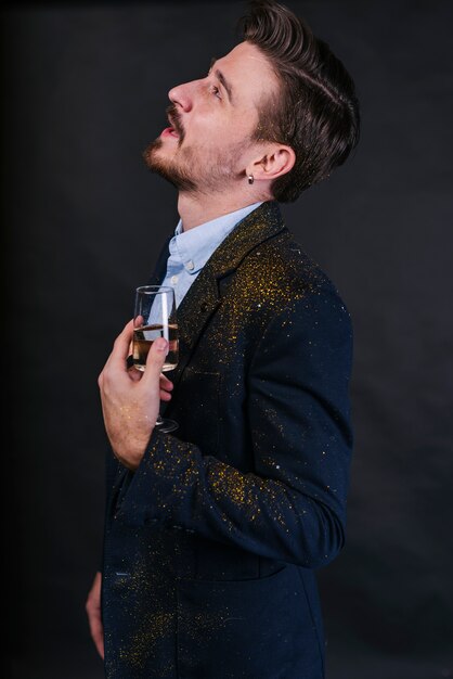 Homme en poudre de paillettes debout avec verre à champagne