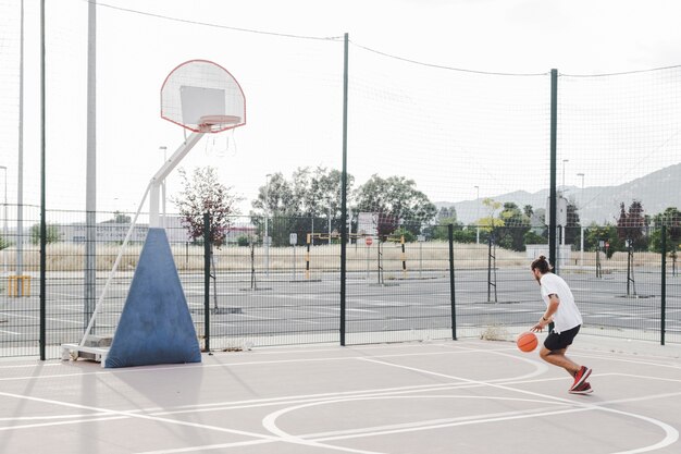 Homme pratiquant le basketball près de cerceau en plein air