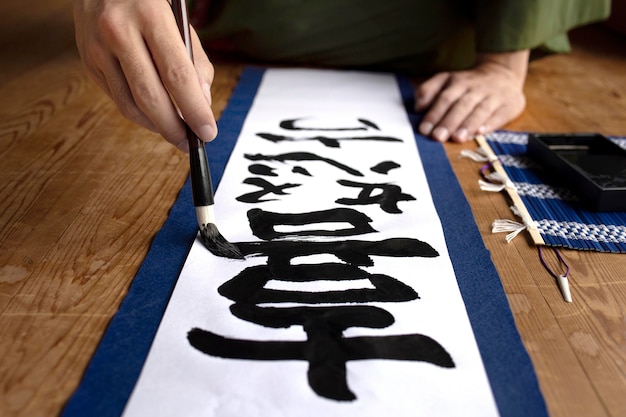 Photo gratuite homme pratiquant l'écriture japonaise avec un pinceau et de l'encre