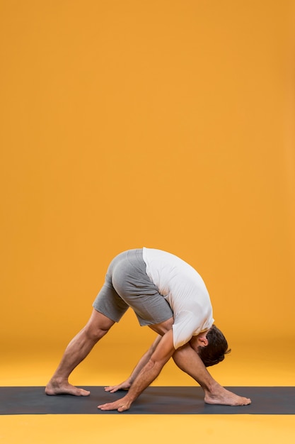 Photo gratuite homme pratiquant la pose de yoga sur tapis