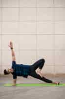 Photo gratuite homme pratiquant le yoga sur tapis à l'extérieur avec espace copie
