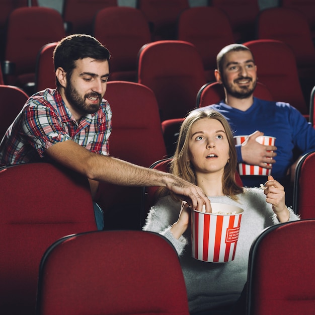 Homme prenant du maïs soufflé de la femme pendant le film