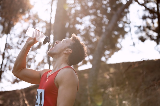 Photo gratuite homme prenant une pause de la course pour boire de l'eau