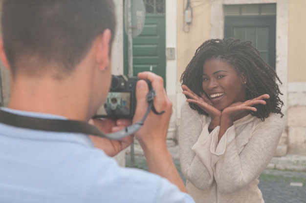 Homme prenant une photo d&#39;une femme noire souriante dans la ville