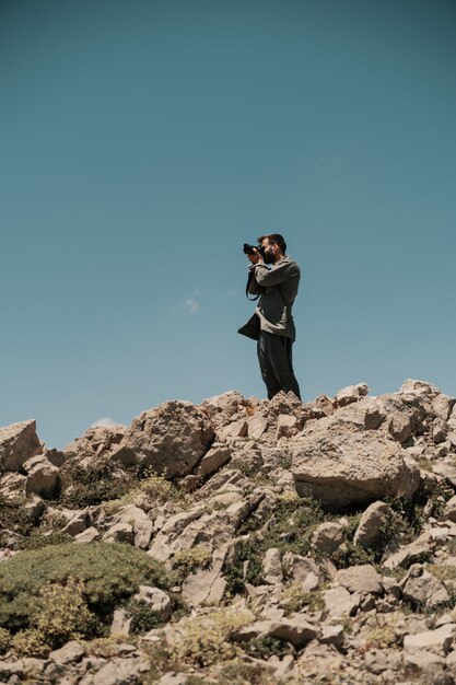 Homme prenant des photos sur une montagne rocheuse