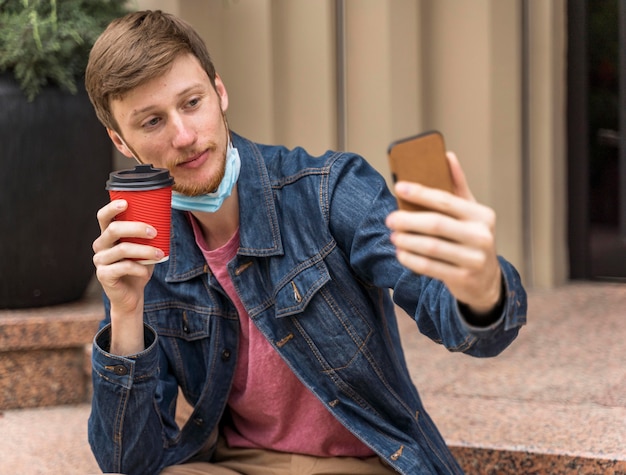 Homme prenant un selfie avec son masque facial vers le bas