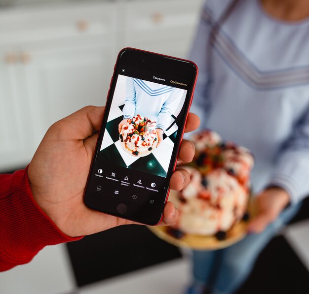 L'homme prend une photo de gâteau sur le téléphone