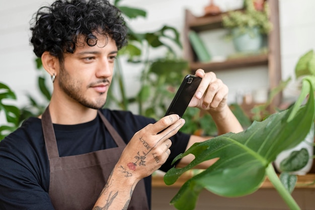 Un homme prend une photo d'une plante d'intérieur à partager sur les réseaux sociaux