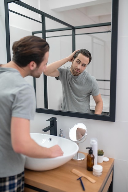 Photo gratuite homme près du miroir se scrutant