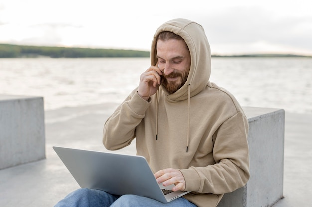 Homme profitant du lac avec ordinateur portable et smartphone