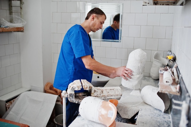 L'homme prothésiste fabriquant une jambe prothétique tout en travaillant en laboratoire fabrique un modèle de plâtre