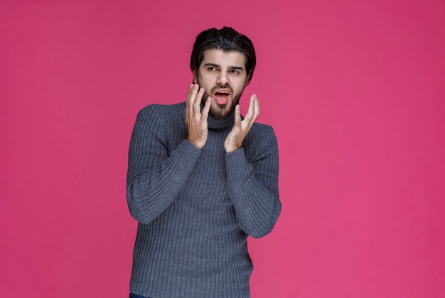 L'homme en pull gris a l'air terrifié et effrayé.