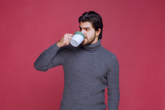 Homme en pull gris, boire du café dans la tasse.