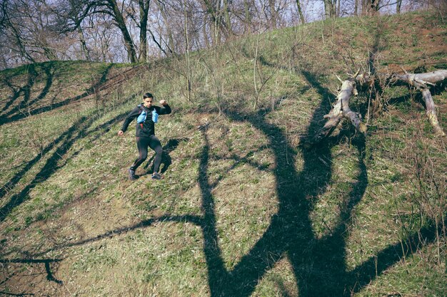 Homme qui court dans un parc ou une forêt contre les arbres