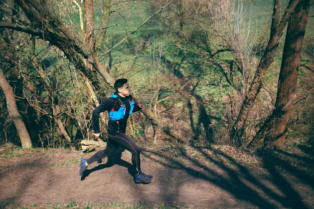 Homme qui court dans un parc ou une forêt contre l'espace des arbres