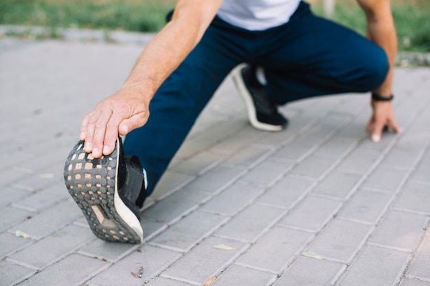 Photo gratuite homme qui s'étend de la jambe sur l'allée du parc