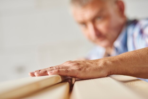 Un homme qui travaille très dur mesure une autre planche de bois