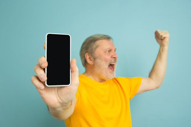 Homme de race blanche montrant l'écran vide du téléphone sur bleu