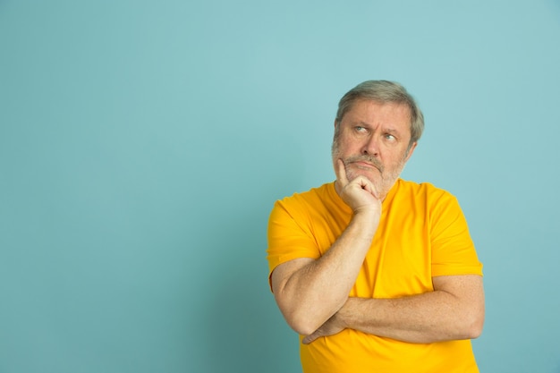 Homme de race blanche réfléchie à côté isolé sur bleu