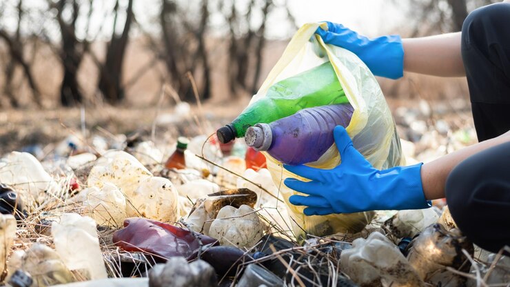 Photo gratuit homme rassemblant des bouteilles en plastique éparpillées sur le sol
