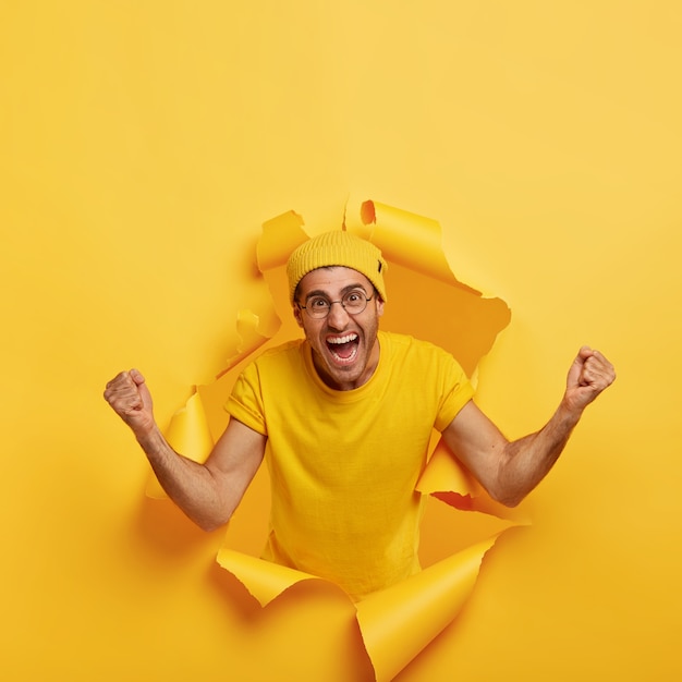 Homme ravi excité posant à travers du papier déchiré