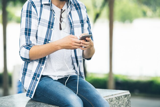 Homme recadré assis sur des escaliers en marbre allumant la musique de l'application