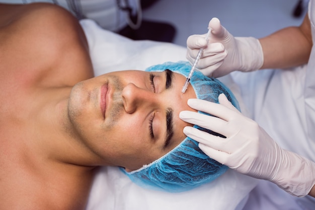 Homme recevant une injection de botox sur son front