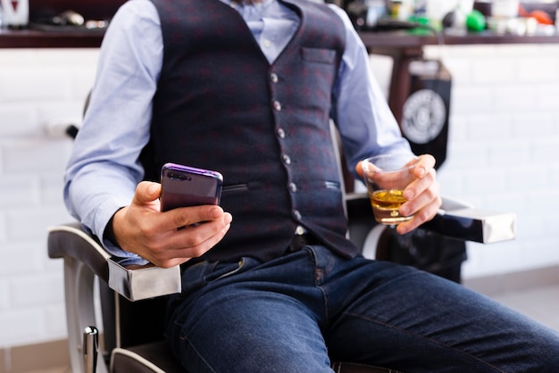 Homme à la recherche sur son téléphone chez le coiffeur