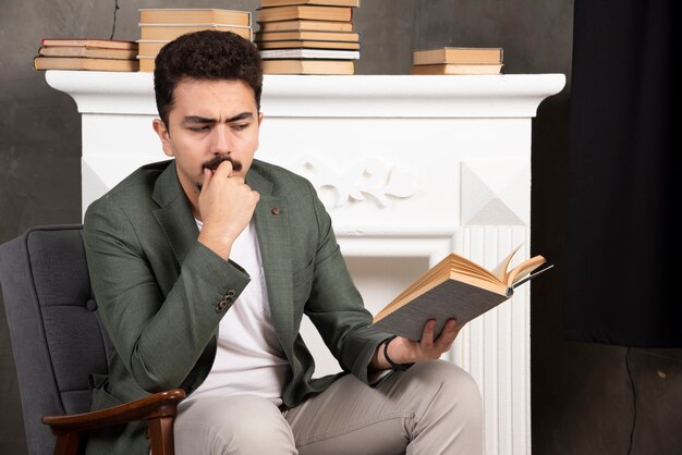 Homme réfléchi et confiant lisant un livre au bureau.