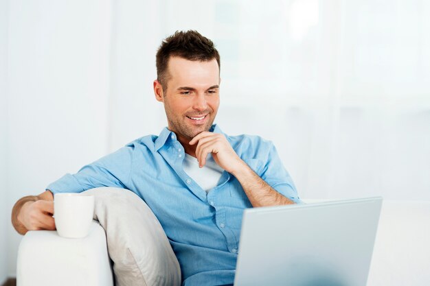 Homme réfléchi avec ordinateur portable et tasse de café