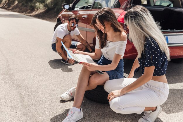 Homme regardant les amies en regardant la carte près de la voiture en panne sur la route