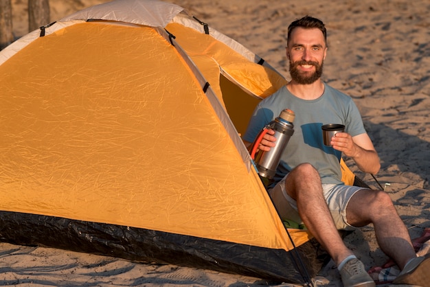 Homme regardant la caméra tenant un thermos