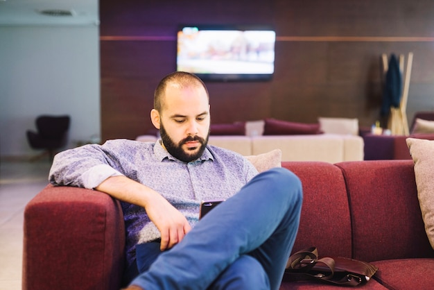 Homme regardant le téléphone et se détendre sur le canapé