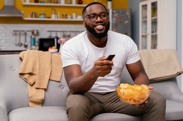 Photo gratuite homme regardant la télévision et manger des chips