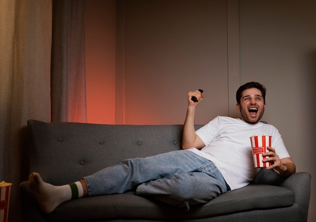 Homme regardant la télévision et manger du pop-corn