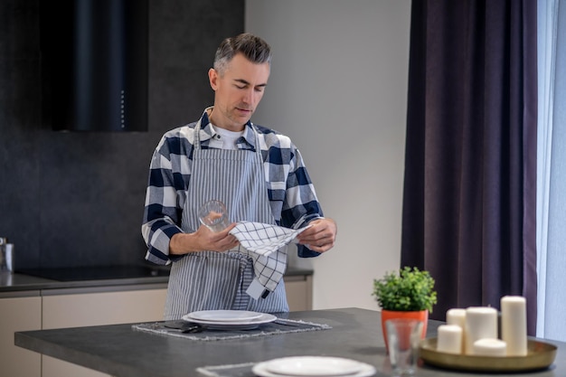 Homme regardant le verre et la serviette dans les mains