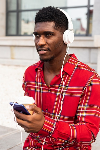 Photo gratuite l'homme regarde ailleurs tout en écoutant de la musique